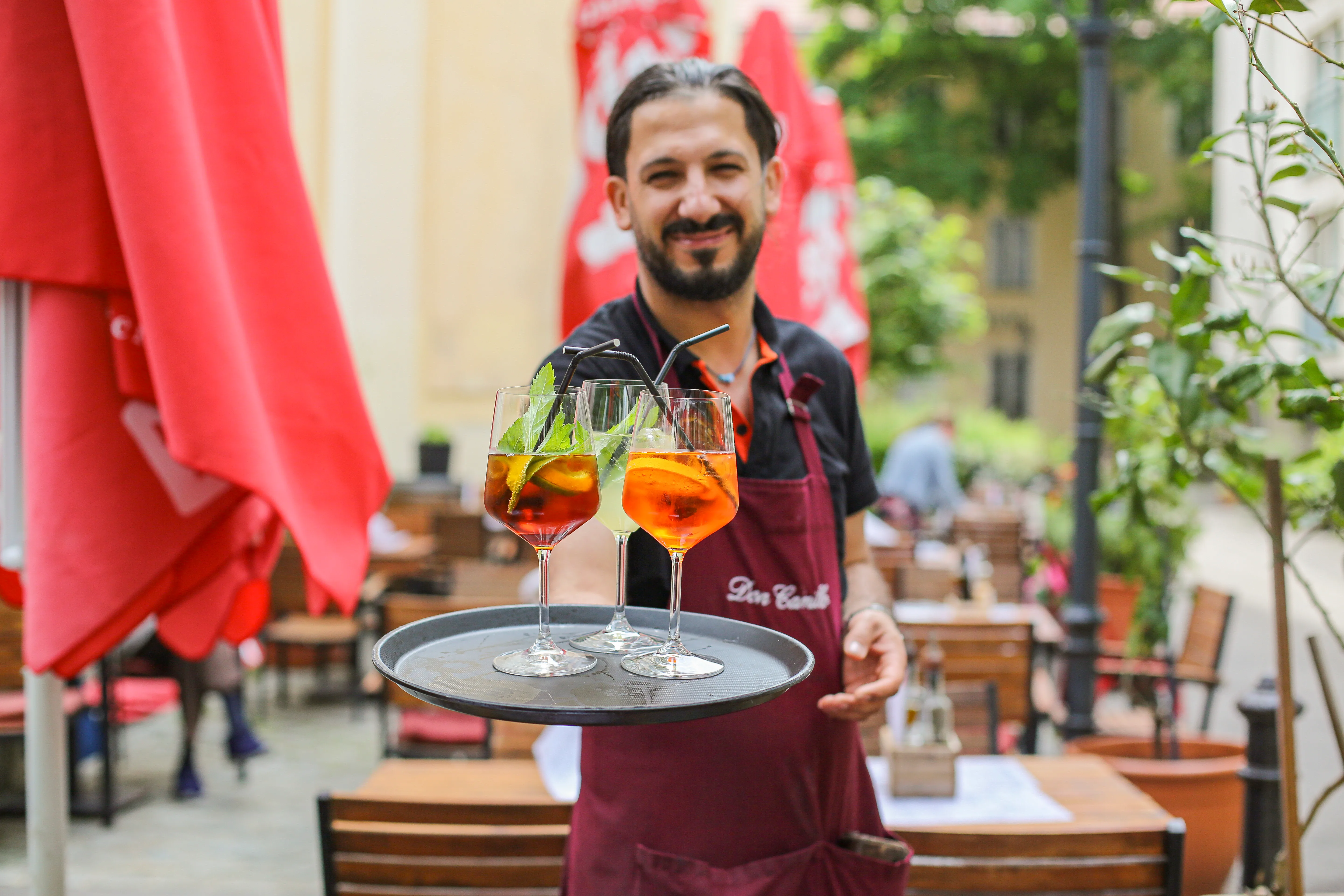 Kellner mit Tablett im Gastgarten